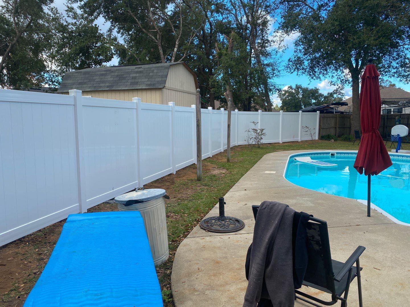 Photo of a white vinyl fence and wood fence surrounding a pool